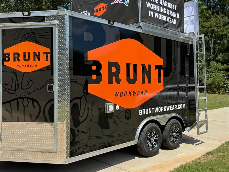 Example custom wrap design: promo trailer in black with bold orange Brunt Workwear logos and a rooftop banner