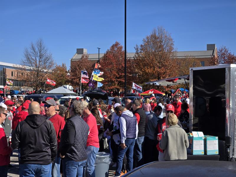 Crowd of fans in red packed around the trailer on a fall day