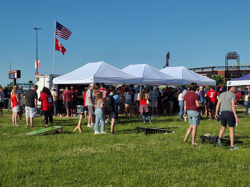Big crowd gathered on a grassy lot around a row of canopies