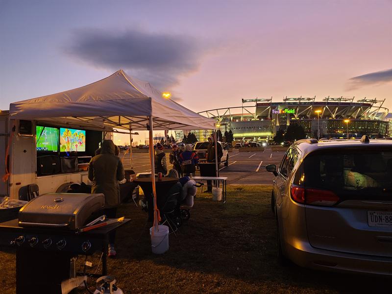 Trailer TVs on at dusk with a grill and seating under a canopy