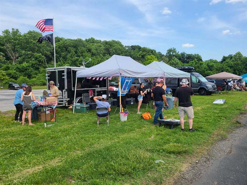 Family tailgate on the grass with canopies and an American flag