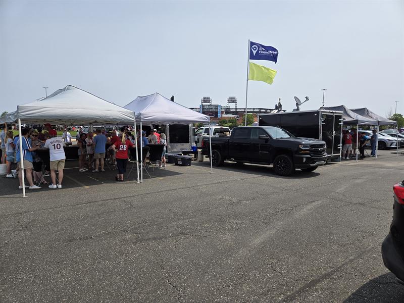 Canopies and trailer with flags flying in a stadium lot