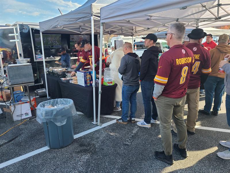 Guests in football jerseys at the food table by the trailer