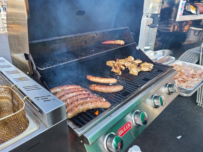 Sausages and chicken cooking on the trailer's stainless steel propane grill