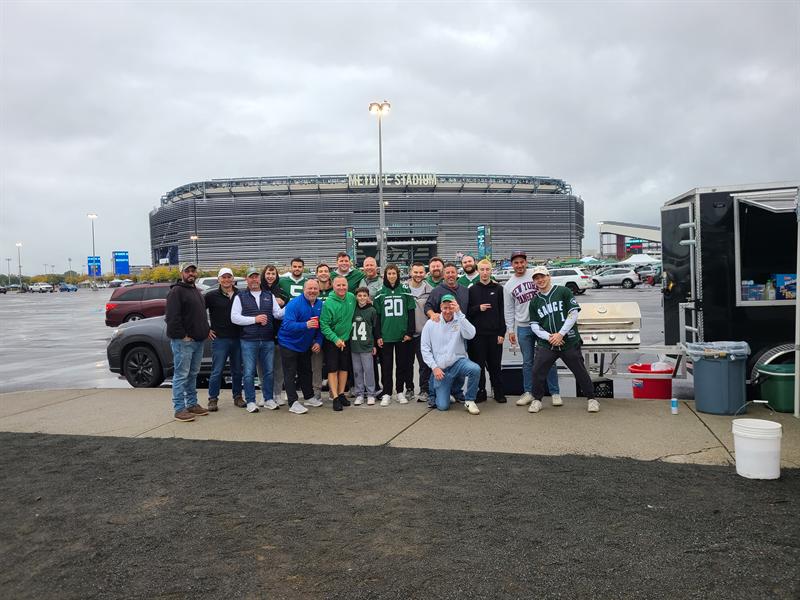 Large group posing by the trailer outside a football stadium