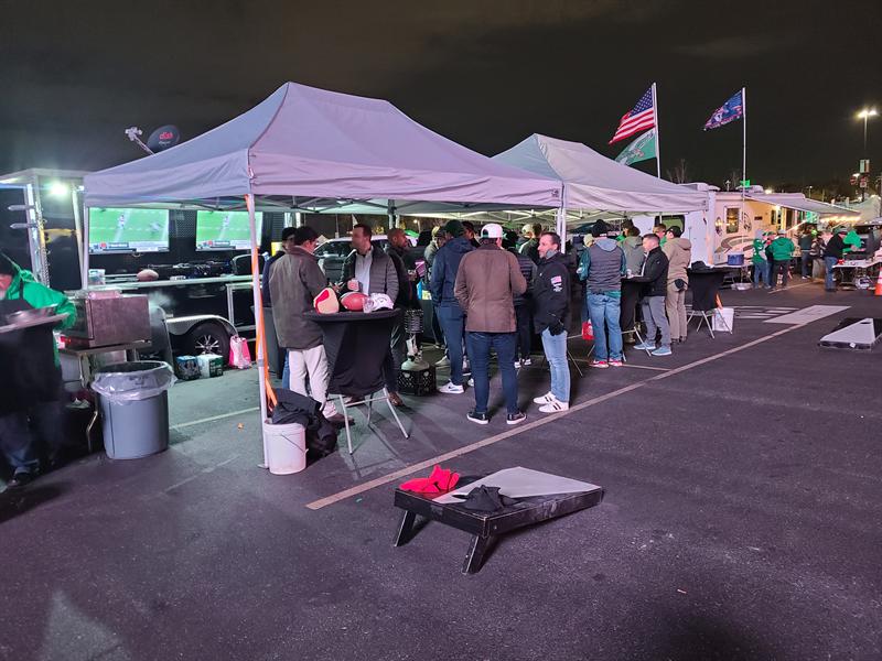 Night tailgate with lit canopies, TVs and cornhole boards