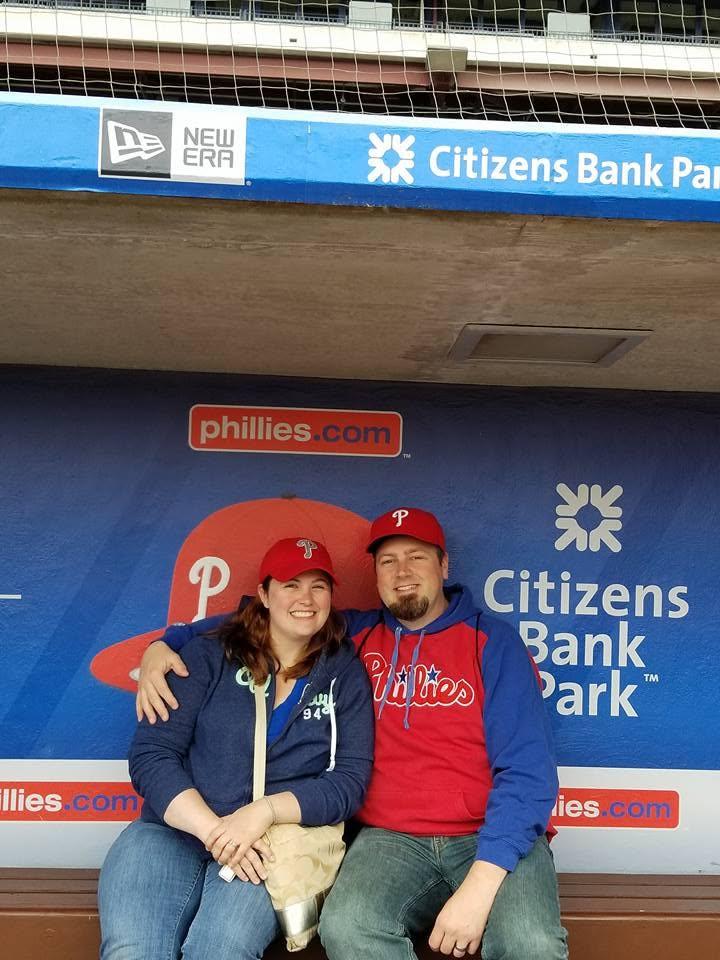 Owners Woody and Jessica Woodward in Phillies gear in the dugout at Citizens Bank Park
