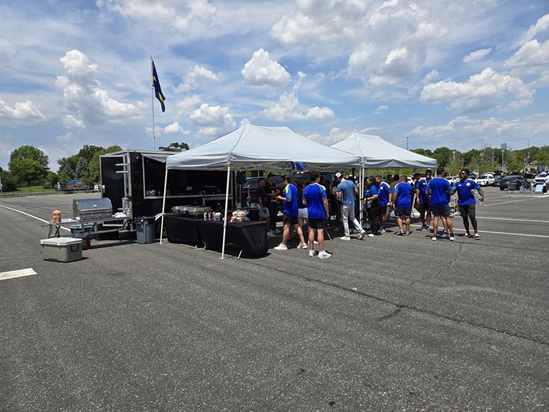 Group in matching blue shirts by the trailer and canopies