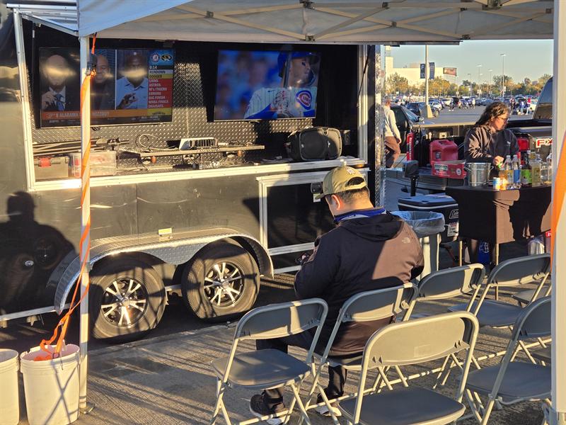 Open side of the tailgate trailer with a mounted TV and folding chairs lined up in front